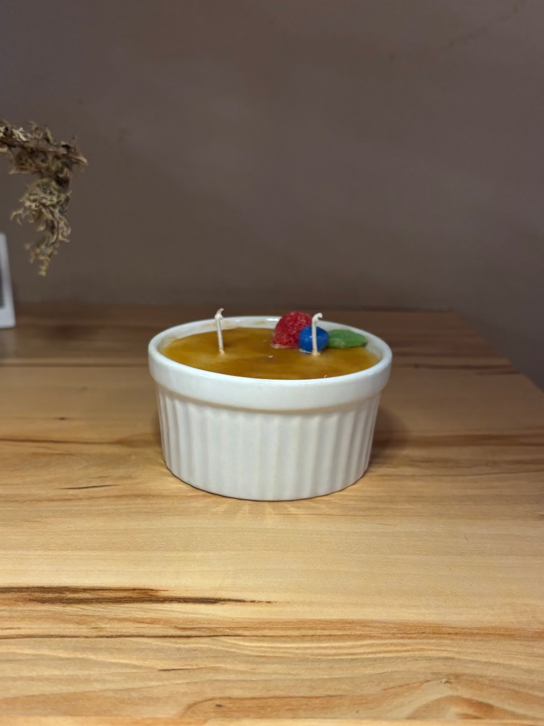 Kerze in einem Glas, die aussieht wie das Dessert Creme Brulee