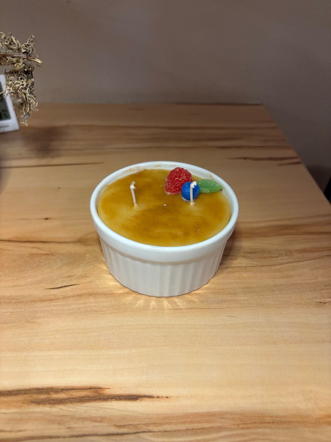 Kerze in einem Glas, die aussieht wie das Dessert Creme Brulee