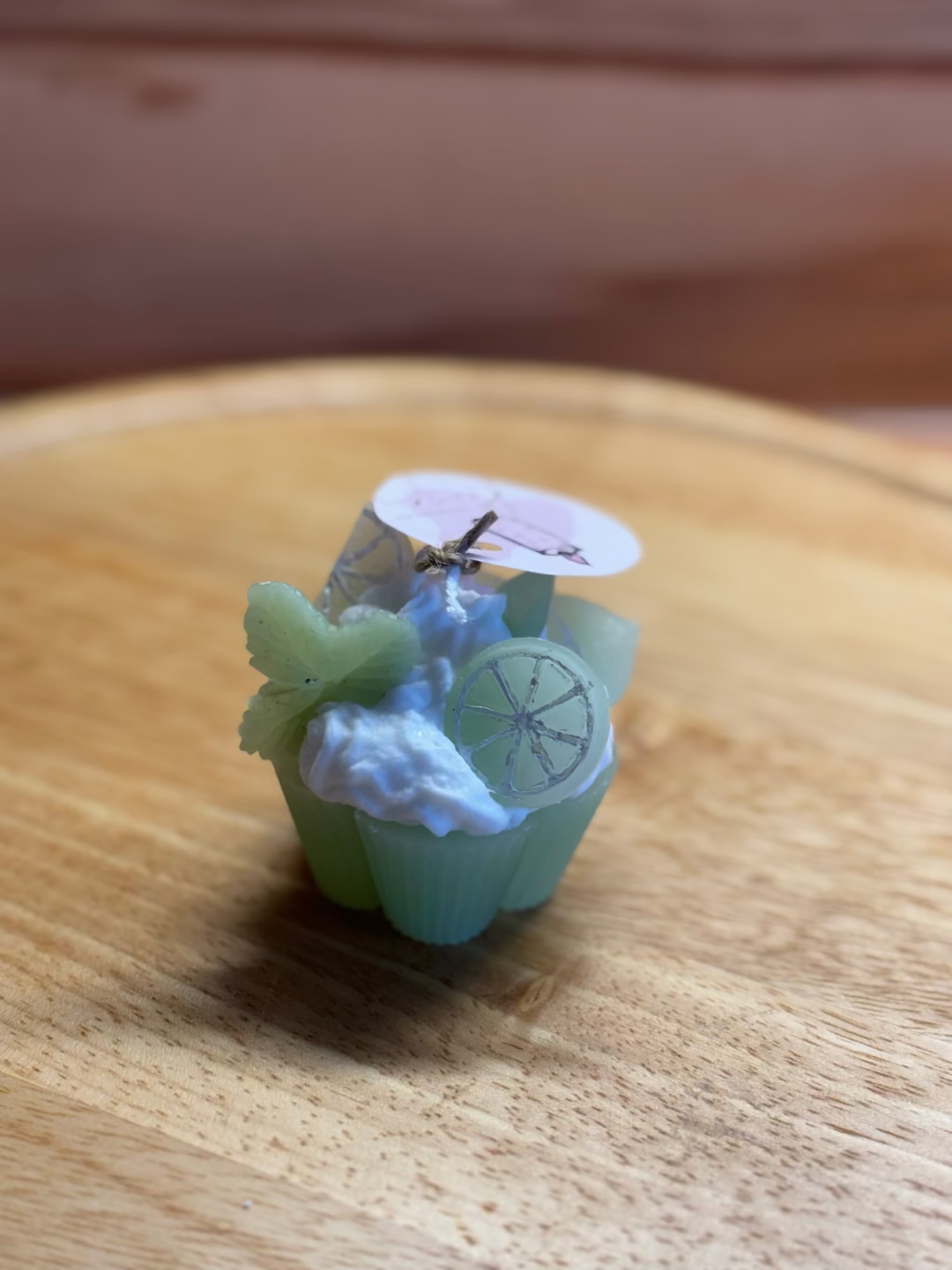 Kerze, die aussieht wie ein grüner Cupcake mit weißer Creme, dekoriert mit Limetten und Minze