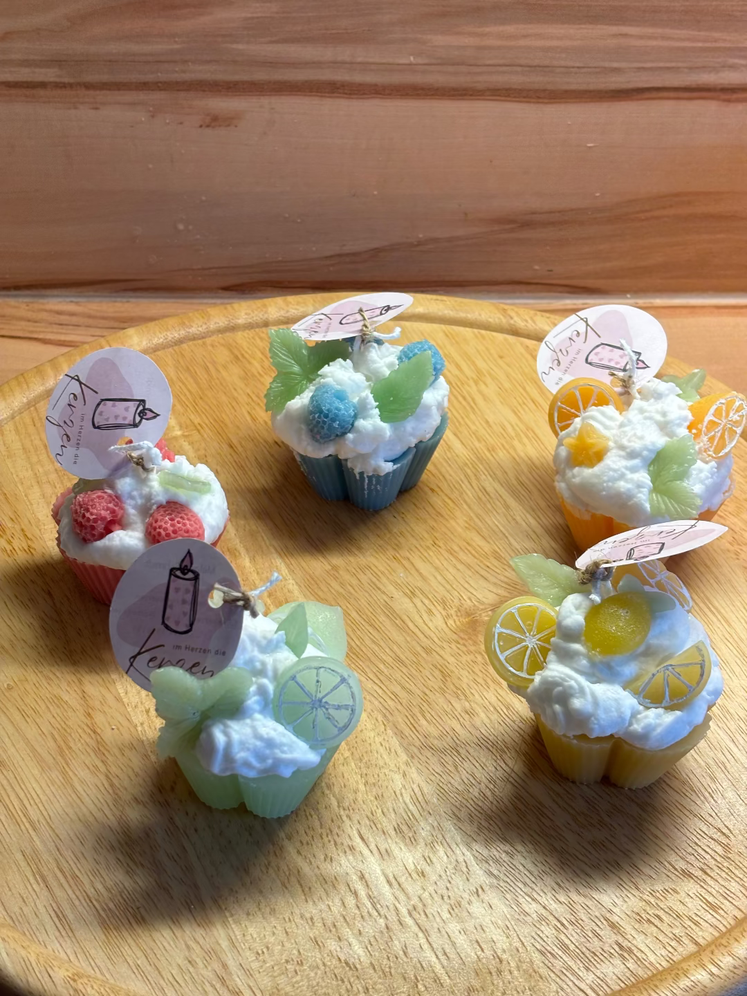 Fünf Kerzen, die aussehen wie Cupcakes in verschiedenen Farben verbunden mit verschiedenen Früchten