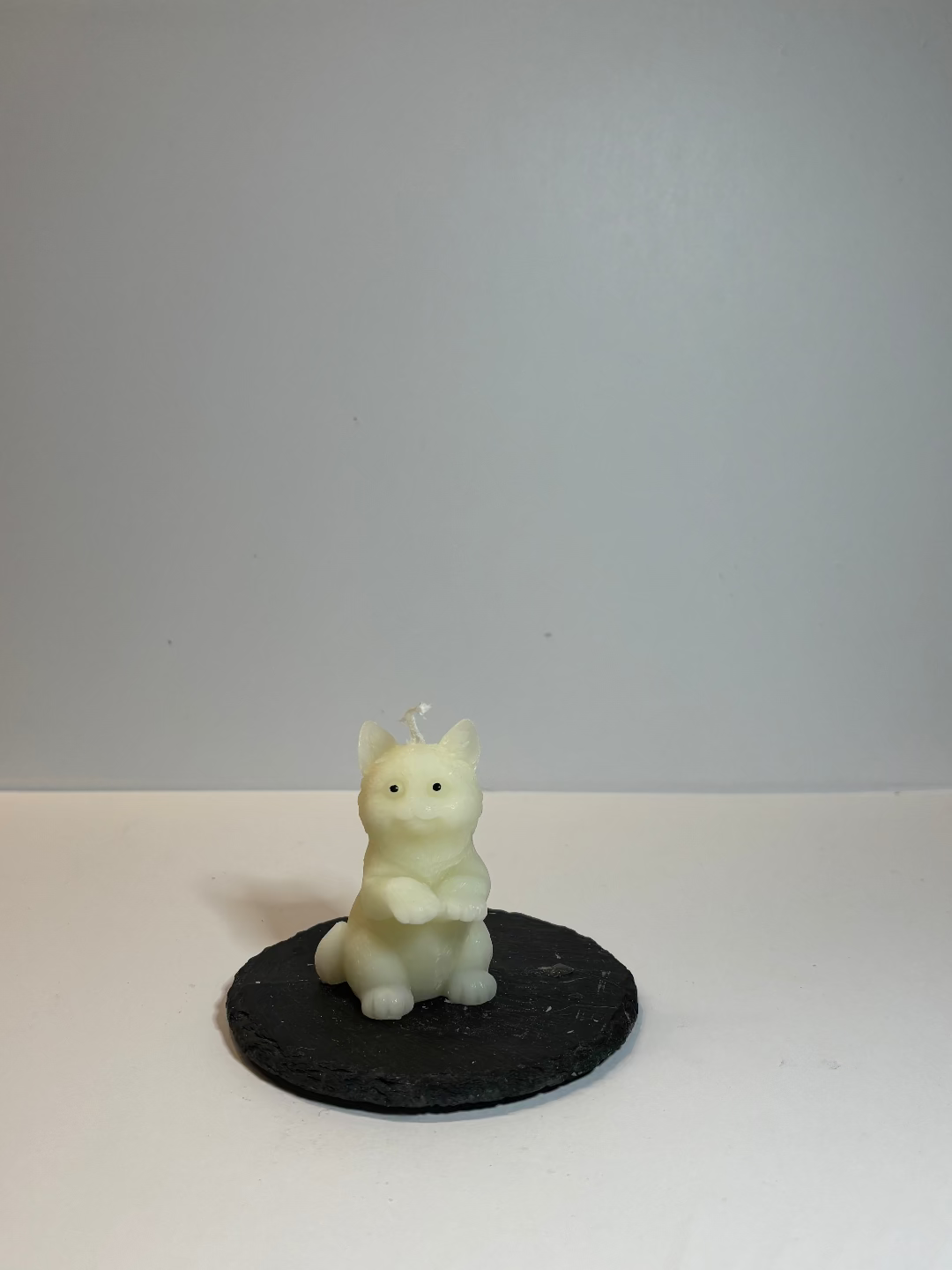 Kerze, die aussieht wie eine kleine Katze, die auf ihren Hinterpfoten steht und die Vorderpfoten nach oben hebt