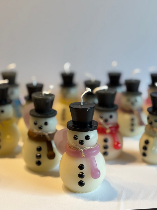 Kerze, die aussieht wie ein Schneemann mit buntem Schal, schwarzem Hut, Knöpfe und Gesicht